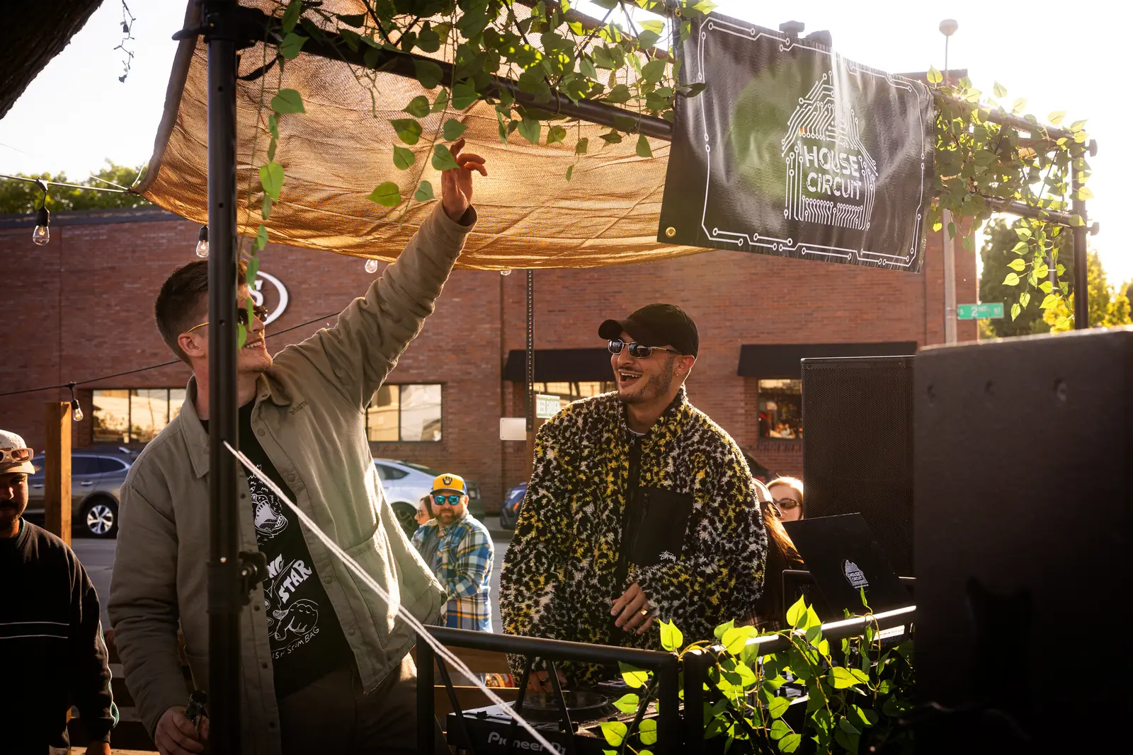 A DJ with a hand in the air at an outdoor House Circuit set
